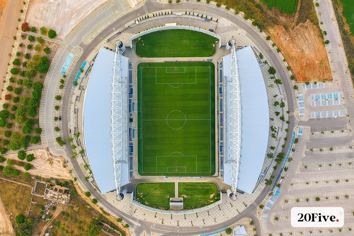 A close aerial crop of a green football pitch and stadium seating
