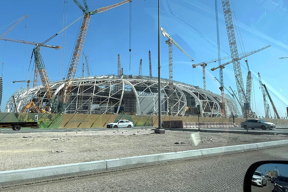 A large stadium under construction with cranes surrounding its curved structure