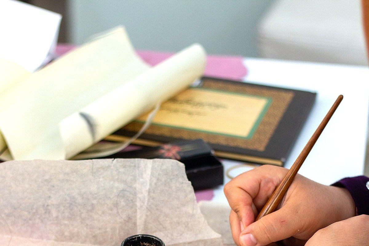 Hands learning Arabic calligraphy during a bright creative workshop